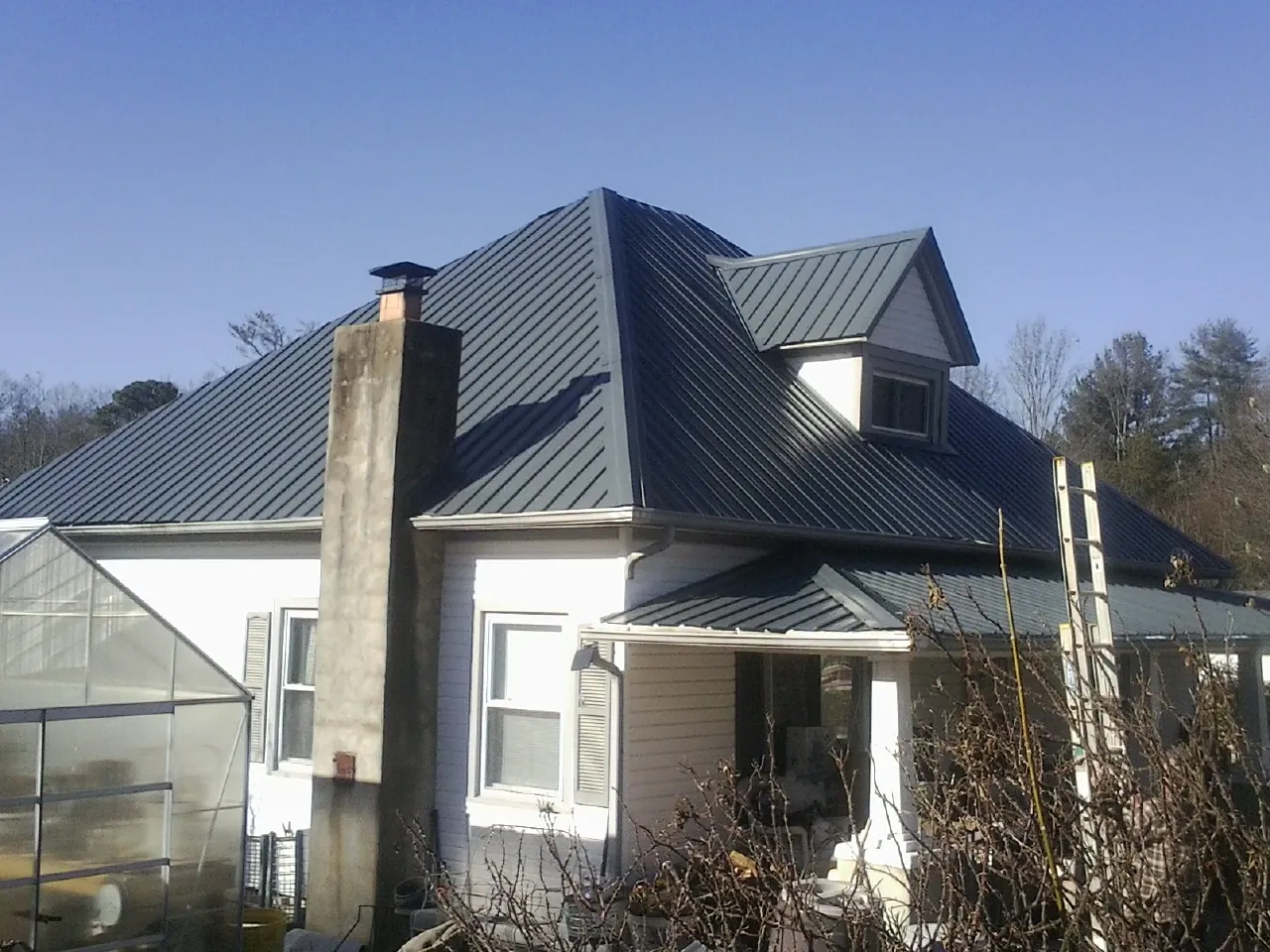 Dark blue standing seam metal roof on a white farmhouse with dormer — Slate & Tile Roof Repair by Roofing Brothers in Chagrin Falls