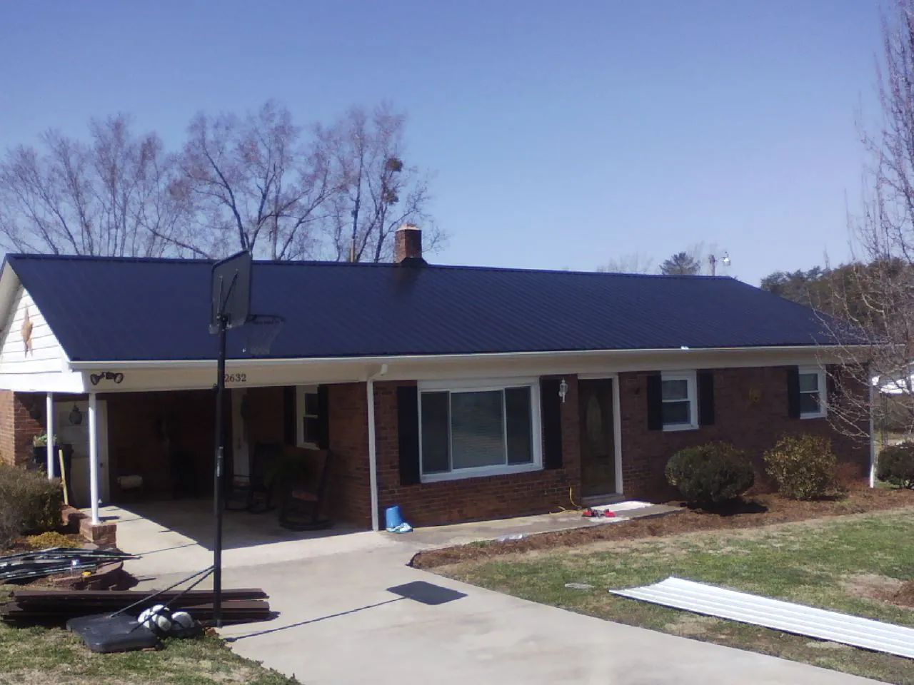 Finished dark blue metal roof on a brick ranch with a carport in Chagrin Falls