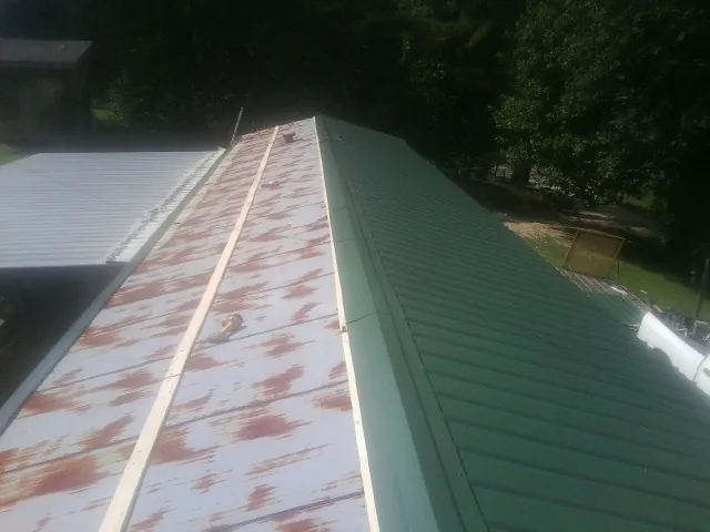 Old rusted panels beside newly installed green metal roofing — Wind Damage Roof Repair by Roofing Brothers in Chagrin Falls