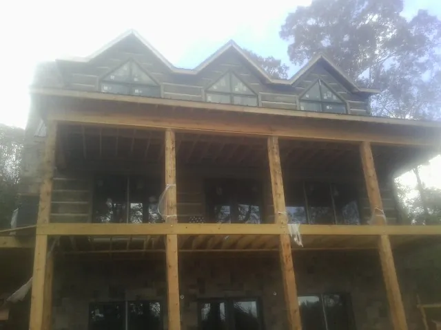 Dormers and porch framing on a large log home under construction — Roof Coating work by our crew in Chagrin Falls