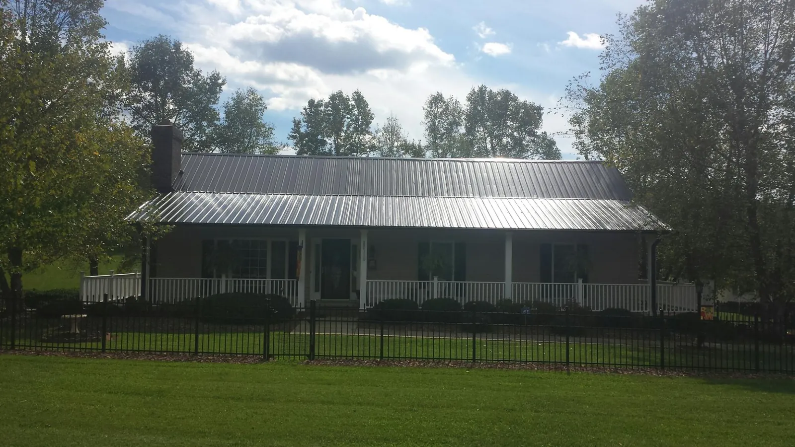 Gray metal roof on a brick ranch with a full width front porch — Gutter Guard Installation work by our crew in Chagrin Falls