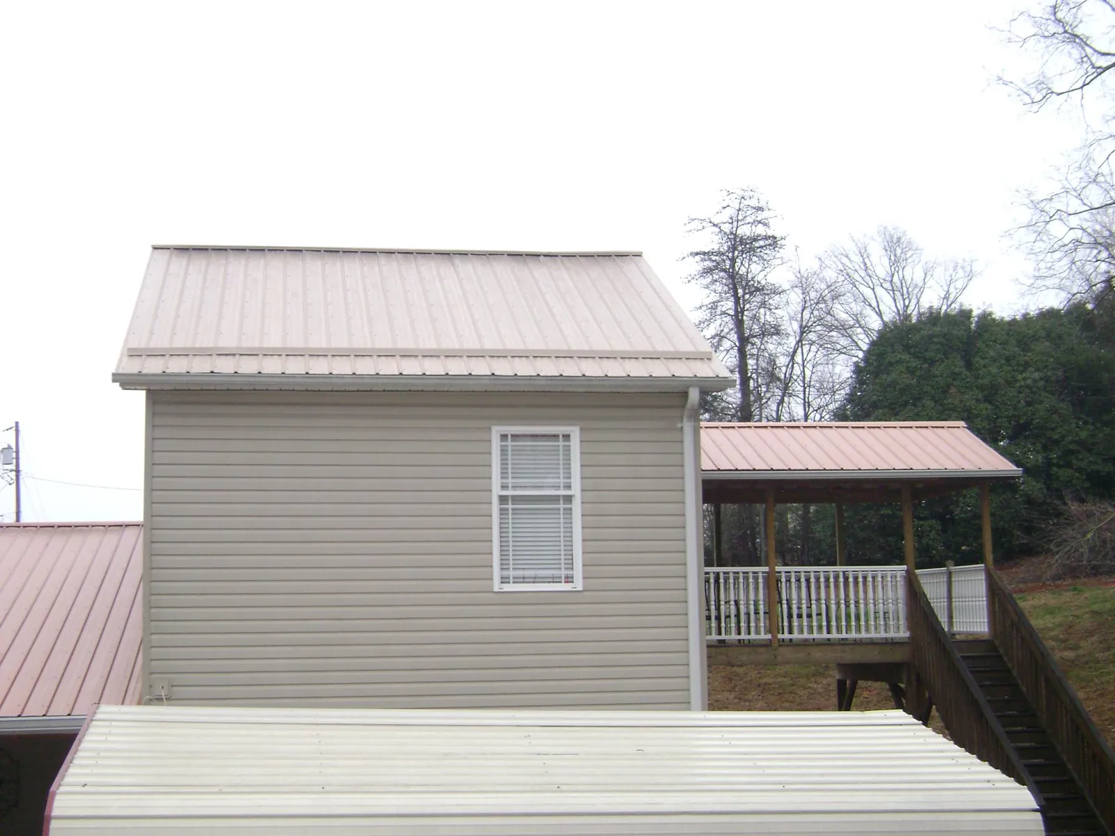 Tan metal roofs on a two story addition and attached porch, from a Roof Replacement job in Chagrin Falls