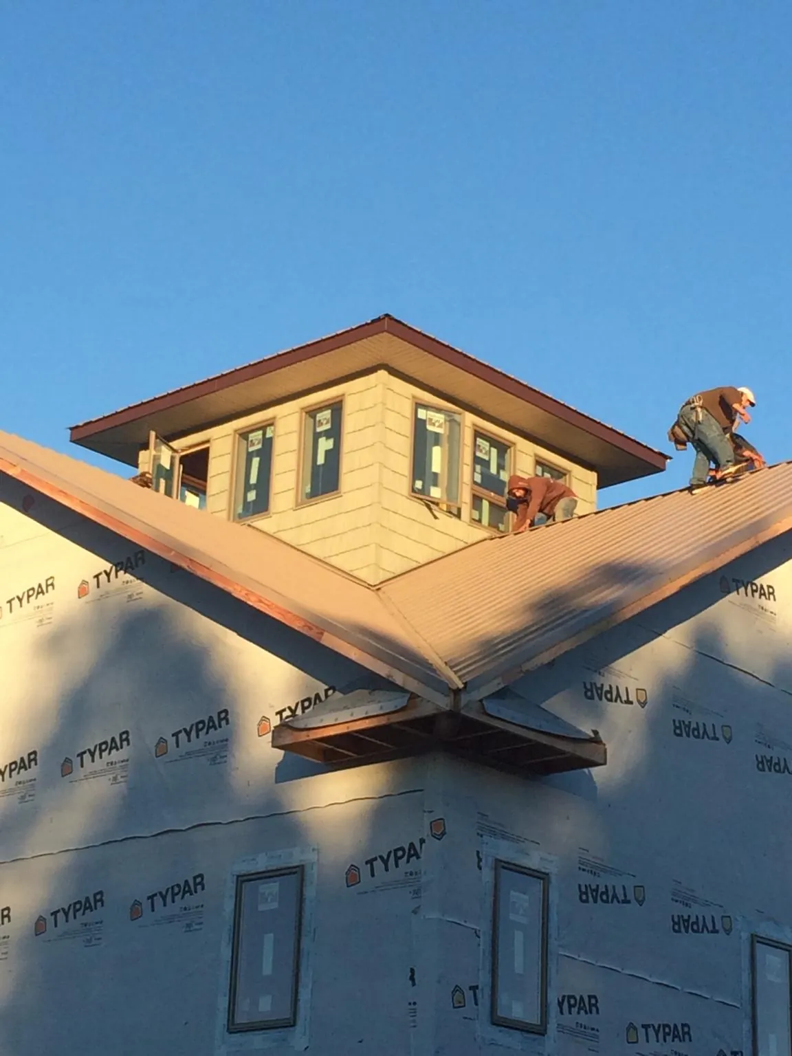 Roofers working around a rooftop cupola on a new metal roof at sunset — Roof Waterproofing in Chagrin Falls by Roofing Brothers